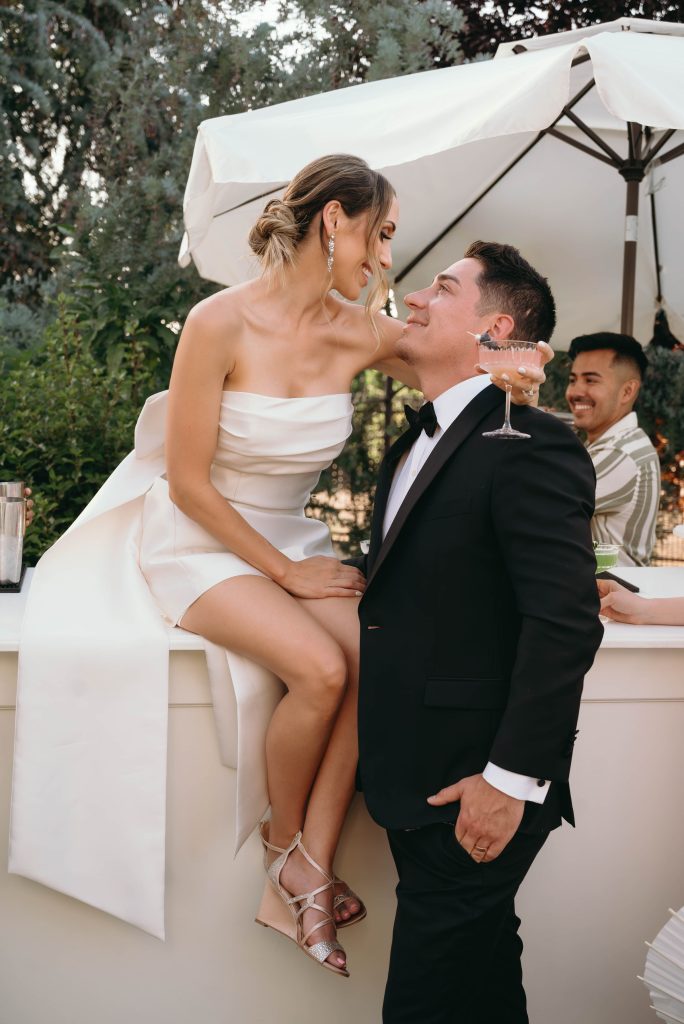 Newly weds looking at each other while the bride is sitting at a counter top